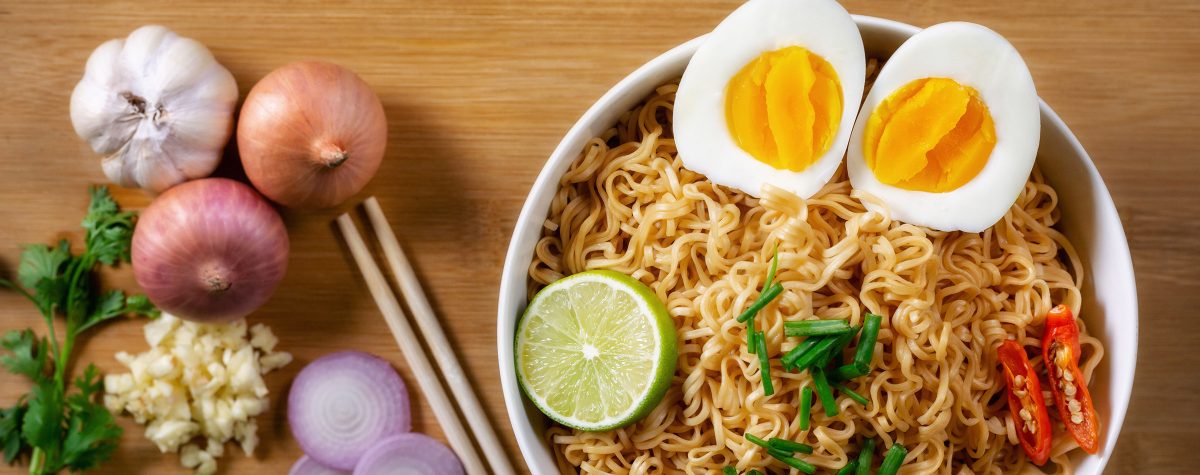 Instant noodles in bowl on wood background top view, Asian meal on a table.