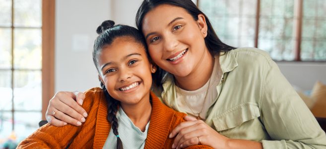 A mother and her daughter hug and smile for the camera.