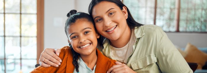 A mother and her daughter hug and smile for the camera.
