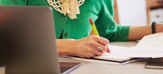 Female Asian teacher at her desk marking studentsÃ¢?? work