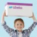 A young boy that is smiling holds up a white and purple box that says “Abeka.”