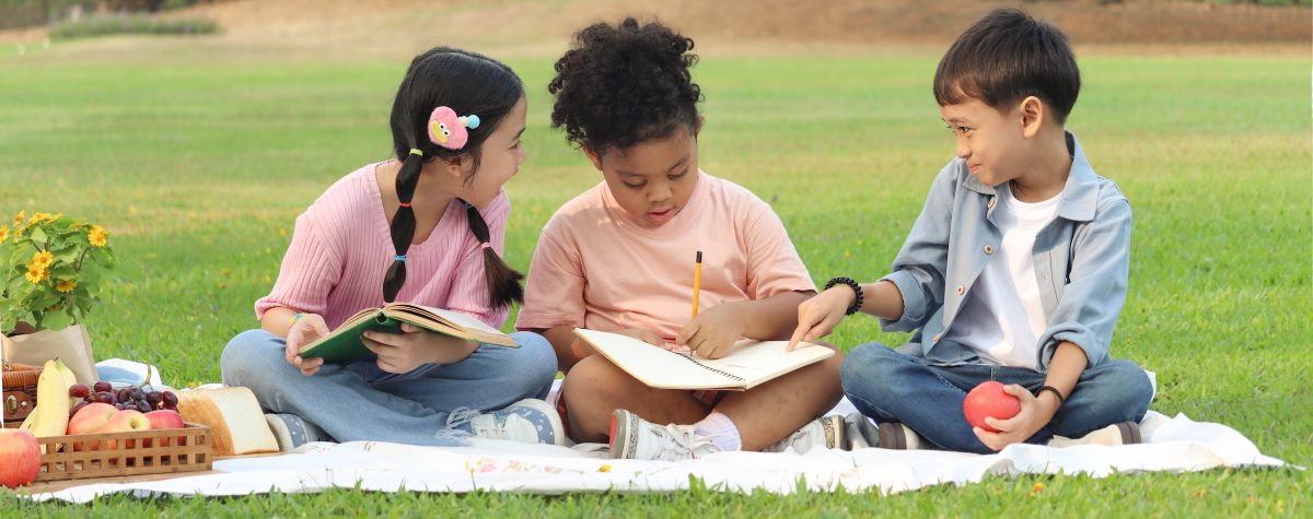 Kids doing summer school on a blanket outside