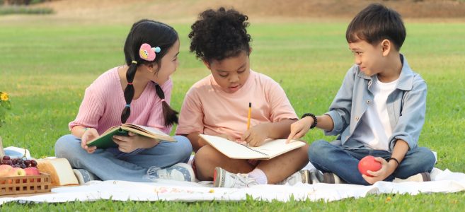Kids doing summer school on a blanket outside