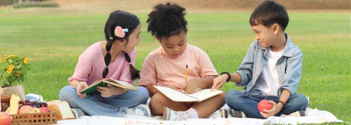 Kids doing summer school on a blanket outside