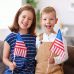 A boy and a girl smile while holding American flags.
